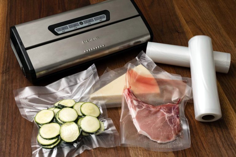 A vacuum sealer machine with food sealed in a bag on a wooden board